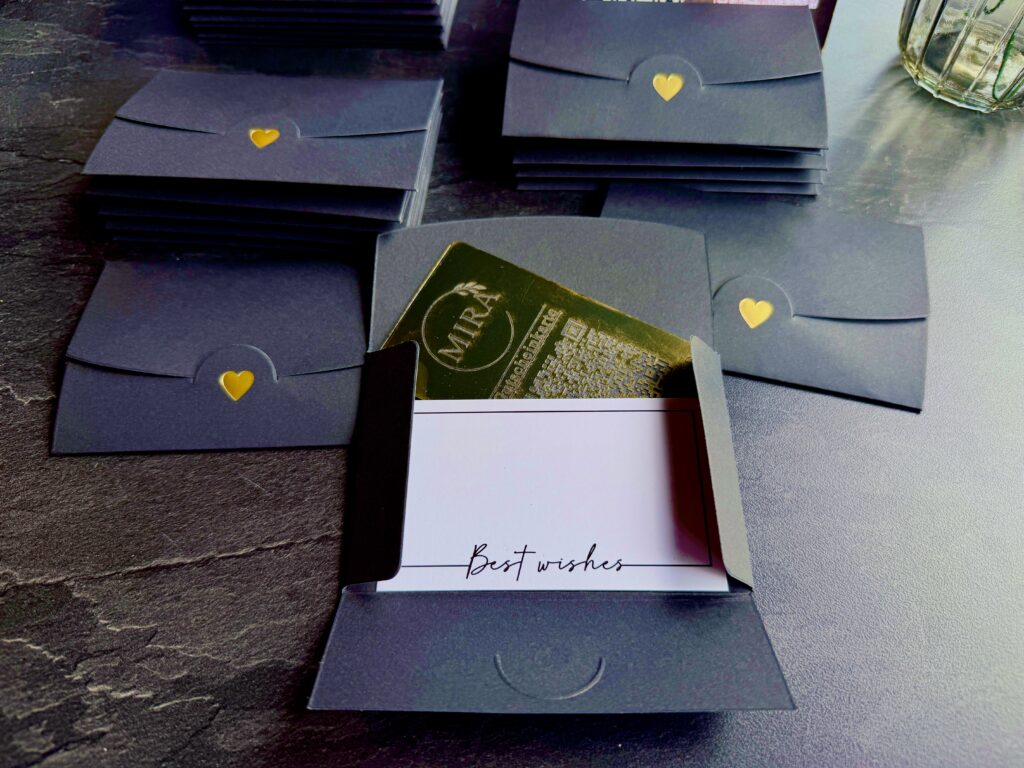 MIRA Gutscheinkarte im dunklen Geschenk-Etui mit goldenem Herz und Grußkarte