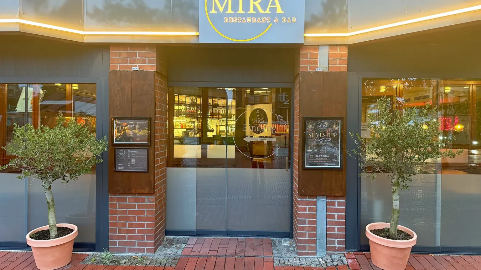 Eingang des MIRA Restaurant & Bar mit Logo und Olivenbäumen, Marktstraße 8a Nordenham