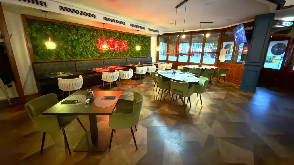 Blick in den Gastraum des MIRA Restaurant Nordenham mit Pflanzenwand und Fensterfront